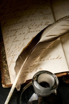 A picture of an old feather pen and writing paper.