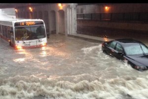 A picture of a bus and a car with flood waters halfway up their vehicles.